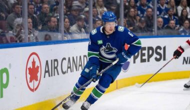 A photo of Vancouver Canucks forward Brock Boeser (#6) controlling the puck with his stick while skating along the boards during an NHL hockey game, looking up-ice.