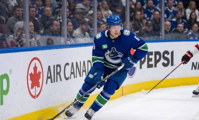 A photo of Vancouver Canucks forward Brock Boeser (#6) controlling the puck with his stick while skating along the boards during an NHL hockey game, looking up-ice.