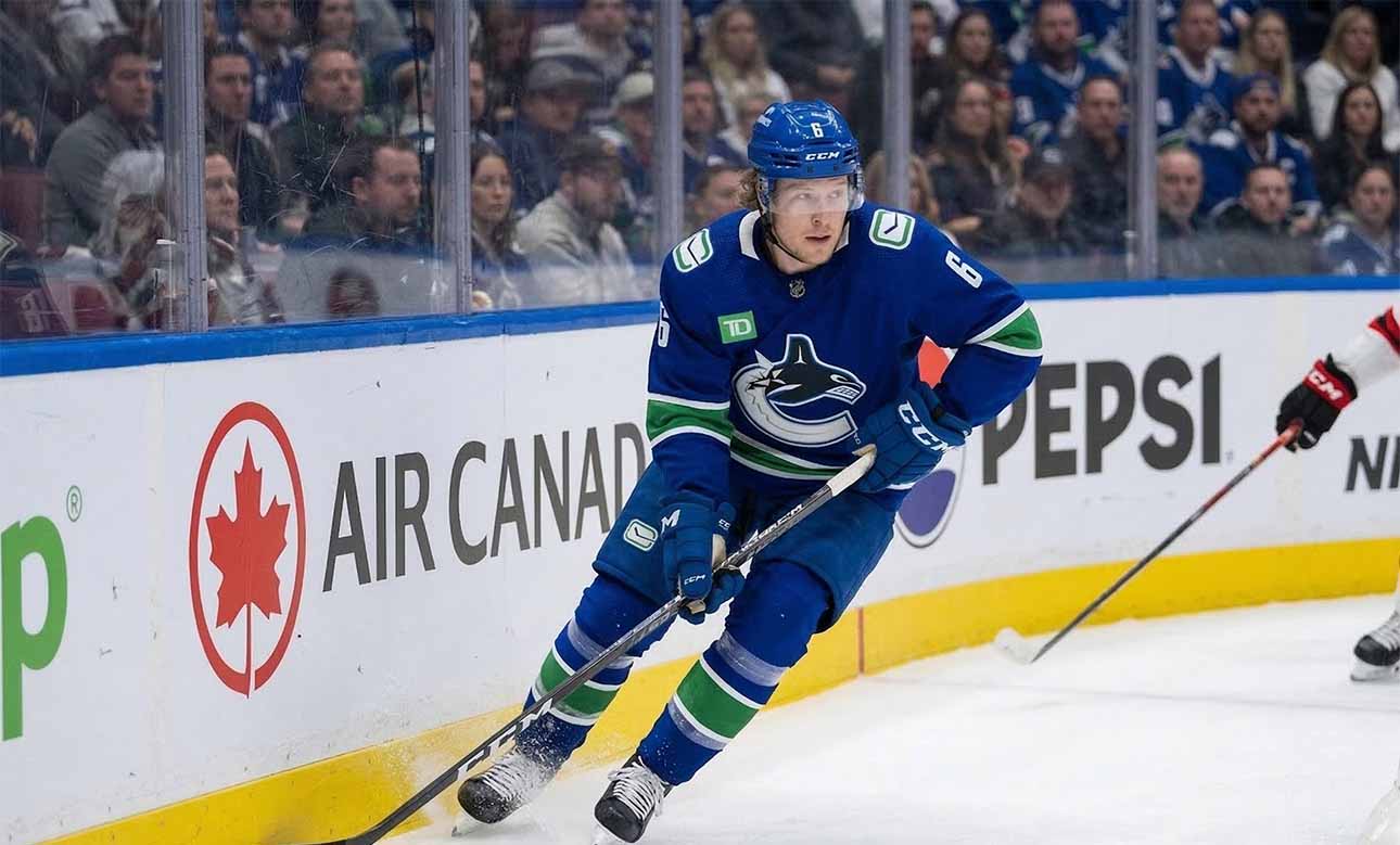 A photo of Vancouver Canucks forward Brock Boeser (#6) controlling the puck with his stick while skating along the boards during an NHL hockey game, looking up-ice.