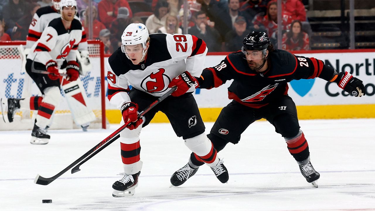Carolina Hurricanes' William Carrier (28) tries to take the puck from New Jersey Devils' Lenni Hameenaho (29) during an NHL hockey game in Raleigh, N.C., Saturday, March 28, 2026. (AP Photo/Karl DeBlaker)