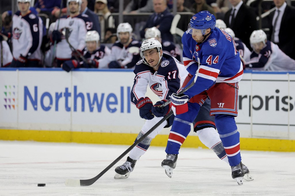 Columbus Blue Jackets' Mason Marchment (17) and New York Rangers' Vladislav Gavrikov (44) fight for the puck.