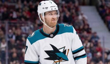 Pensive Dougie Hamilton wearing a white San Jose Sharks away uniform with teal accents, illustrating potential NHL trade rumors.