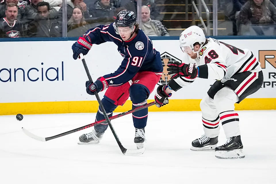 Blue Jackets center Kent Johnson (91) passes over Blackhawks defenseman Matt Grzelcyk (48) on Feb. 4.