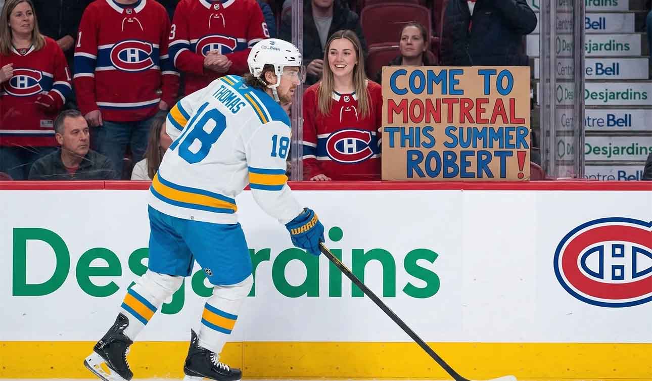 St. Louis Blues player Robert Thomas skates as a Montreal Canadiens fan holds a homemade sign saying "COME TO MONTREAL THIS SUMMER ROBERT!", fueled by persistent Canadiens NHL trade rumors.