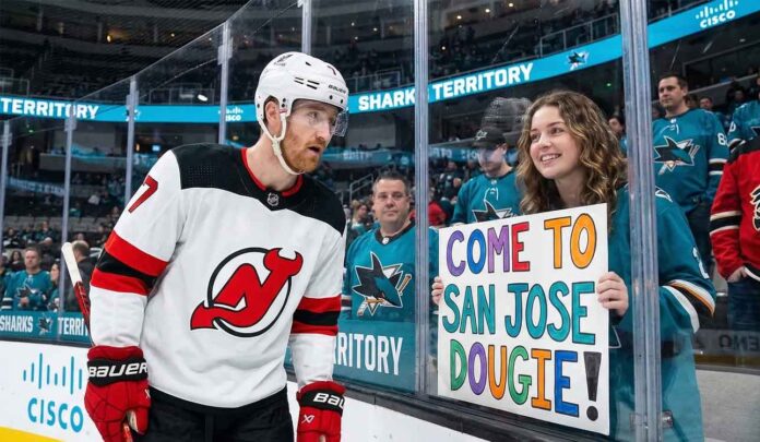 New Jersey Devils defenseman Dougie Hamilton looks at a hand-painted sign held by a smiling San Jose Sharks fan through the arena glass. The sign reads 'COME TO SAN JOSE DOUGIE!', referencing player movement and trade rumors between the two teams.
