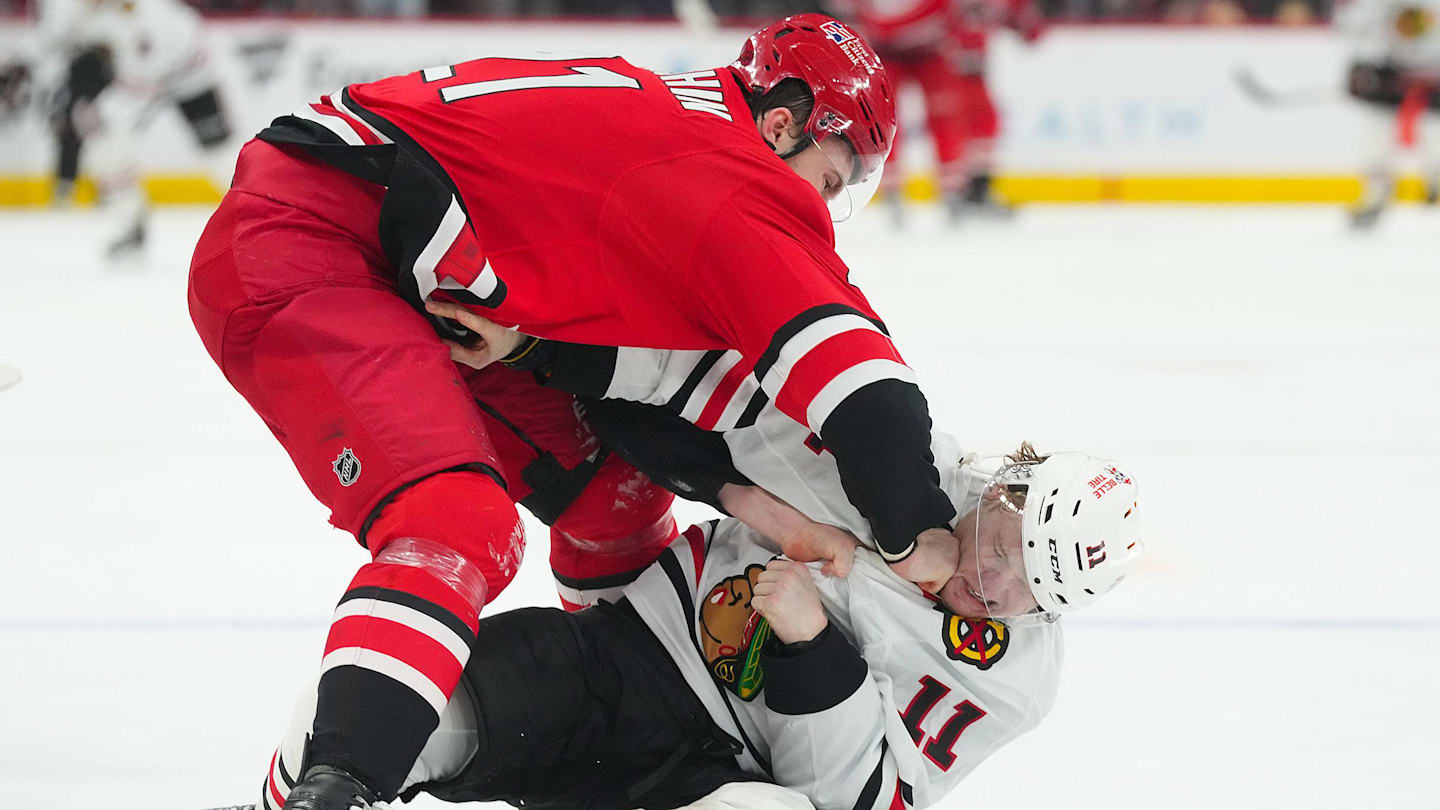 Jan 22, 2026; Raleigh, North Carolina, USA;  Carolina Hurricanes defenseman Alexander Nikishin (21) and Chicago Blackhawks center Oliver Moore (11) fight during the second period at Lenovo Center. Mandatory Credit: James Guillory-Imagn Images