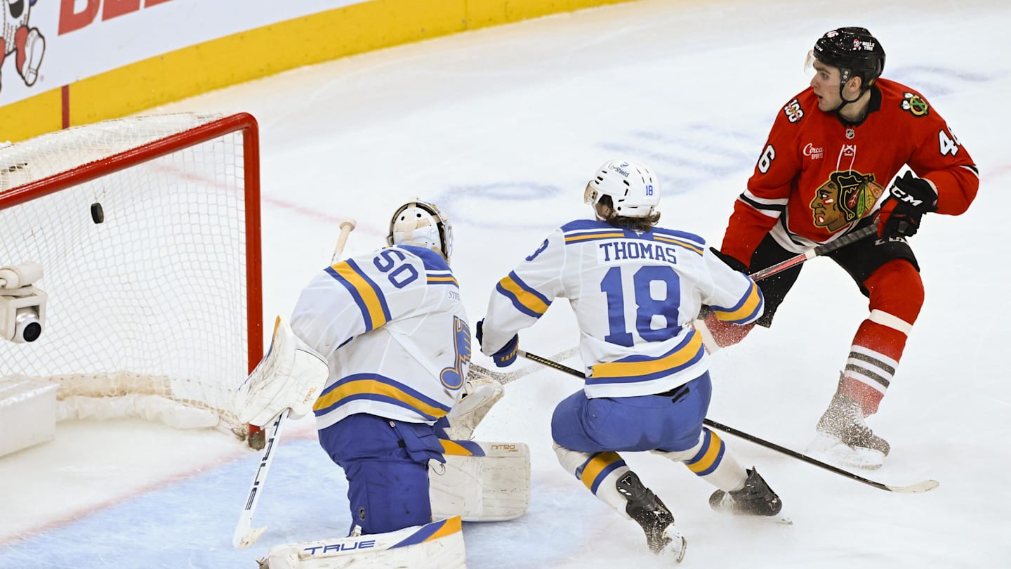 Jan 7, 2026; Chicago, Illinois, USA;  Chicago Blackhawks defenseman Louis Crevier (46) scores a goal past St. Louis Blues goaltender Jordan Binnington (50) and center Robert Thomas (18) during the third period at the United Center. Mandatory Credit: Matt Marton-Imagn Images
