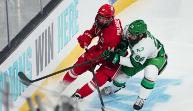 Apr 9, 2026; Las Vegas, Nevada, UNITED STATES; Wisconsin Badgers defenseman Joe Palodichuk (14) and North Dakota Fighting Hawks forward Dylan James (26) battle for the puck in the first period in the semifinals of the NCAA men's ice hockey Frozen Four at T-Mobile Arena. Mandatory Credit: Stephen R. Sylvanie-Imagn Images