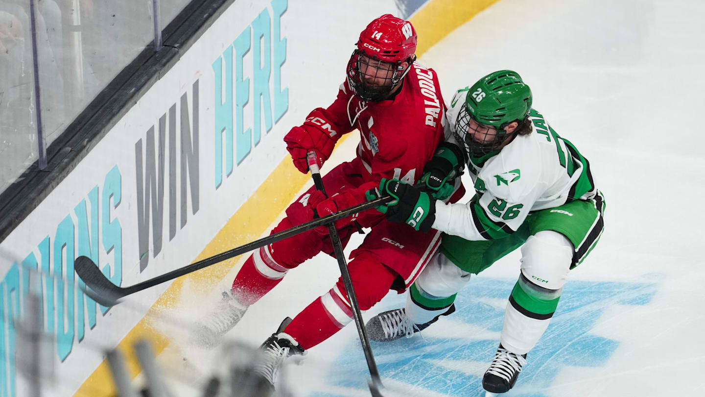 Apr 9, 2026; Las Vegas, Nevada, UNITED STATES; Wisconsin Badgers defenseman Joe Palodichuk (14) and North Dakota Fighting Hawks forward Dylan James (26) battle for the puck in the first period in the semifinals of the NCAA men's ice hockey Frozen Four at T-Mobile Arena. Mandatory Credit: Stephen R. Sylvanie-Imagn Images