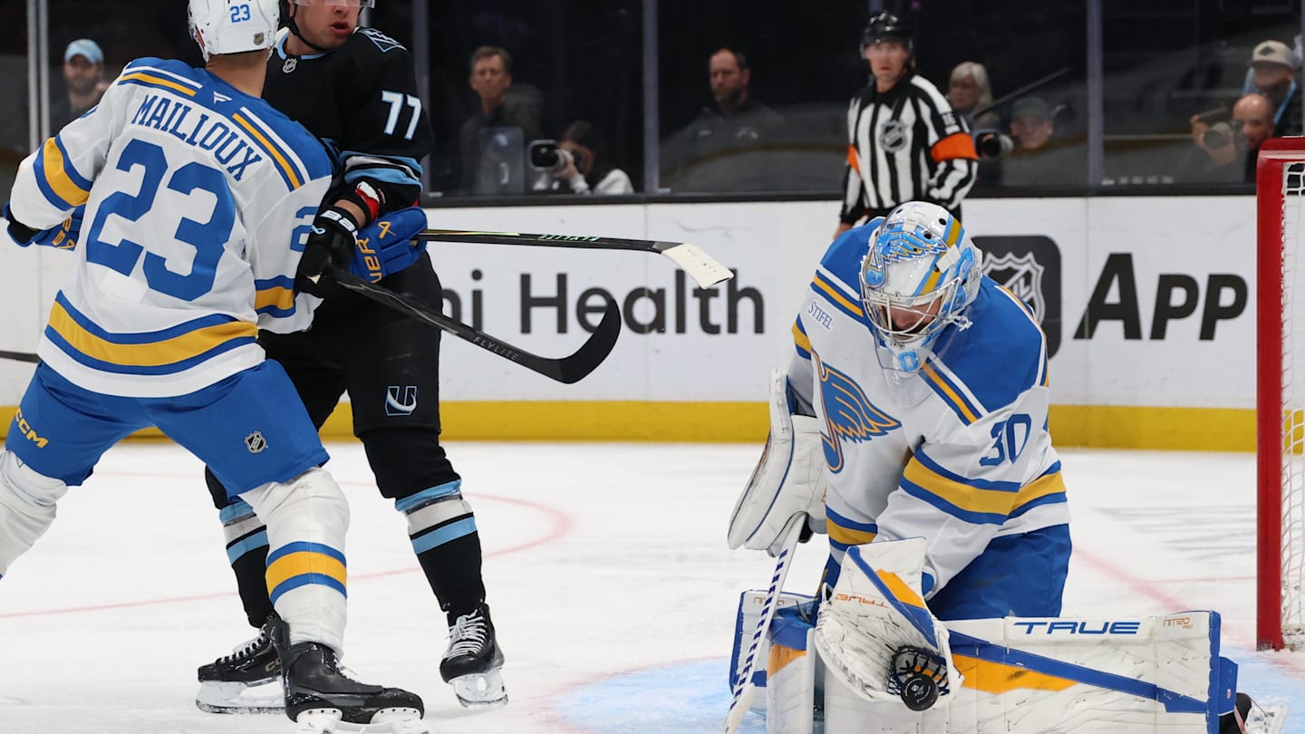 Apr 16, 2026; Salt Lake City, Utah, USA; St. Louis Blues goaltender Joel Hofer (30) blocks a shot while defenseman Logan Mailloux (23) and right wing JJ Peterka (77) play for a rebound during the first period at Delta Center. Mandatory Credit: Rob Gray-Imagn Images