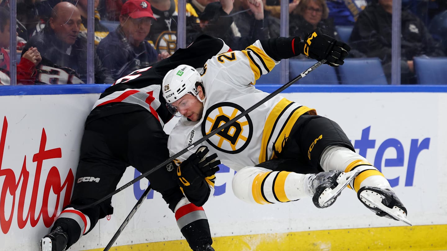 Dec 27, 2025; Buffalo, New York, USA;  Boston Bruins defenseman Andrew Peeke (26) tries to check Buffalo Sabres center Noah Ostlund (86) as he goes after the puck during the second period at KeyBank Center. Mandatory Credit: Timothy T. Ludwig-Imagn Images