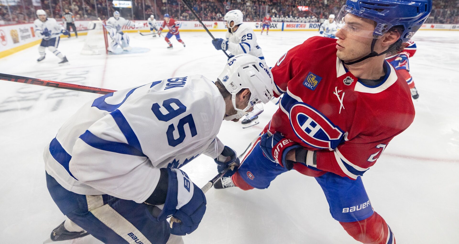 Two hockey players grapple along the boards in a close-up view.