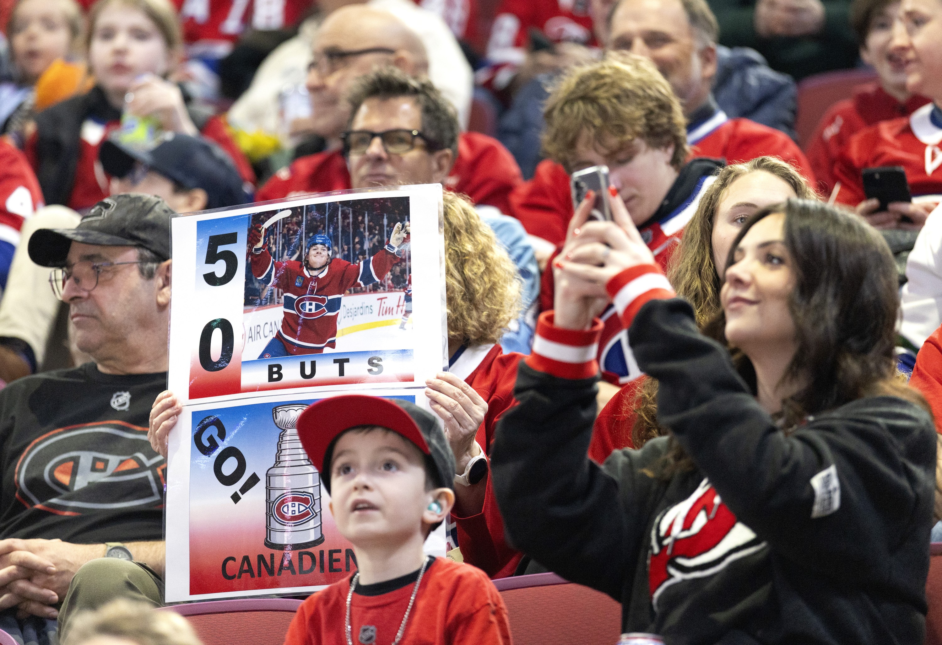 Fans in the stands at the Bell Centre hold signs cheering on Cole Caufield, who was seeking his 50th goal.