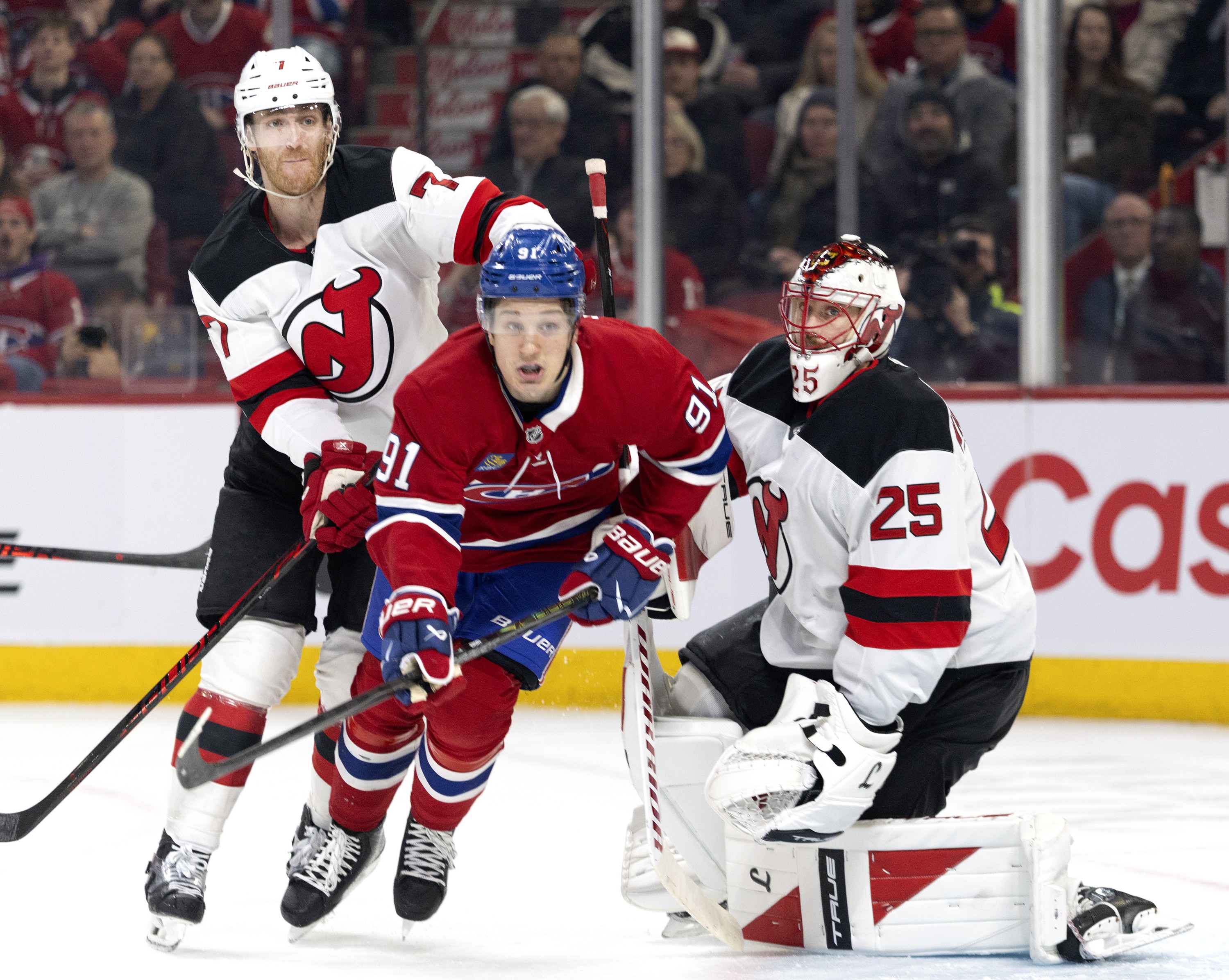 Montreal Canadiens centre Oliver Kapanen takes a hit from behind by New Jersey Devils defenceman Jonas Siegenthaler as he tries to clear New Jersey Devils goaltender Jacob Markstrom.