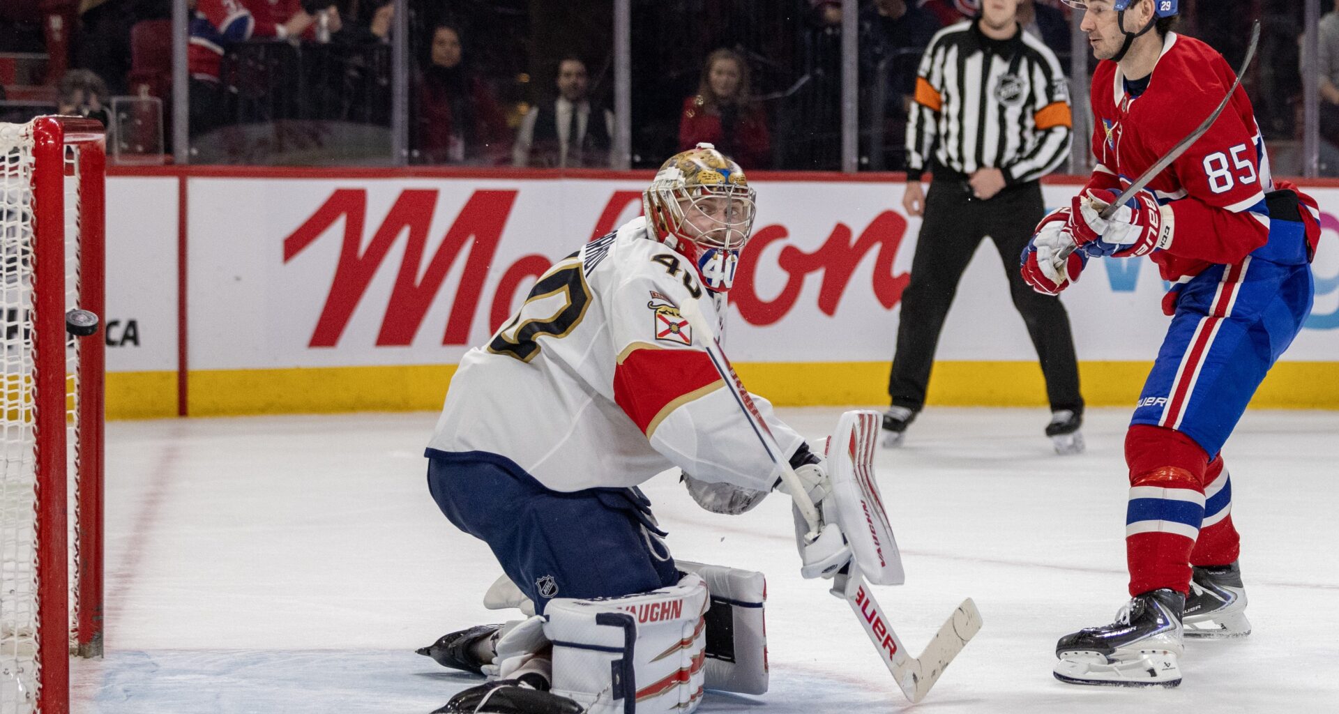 The puck flies into the net behind the Florida Panthers goalie while a Canadiens player follows through on a shot