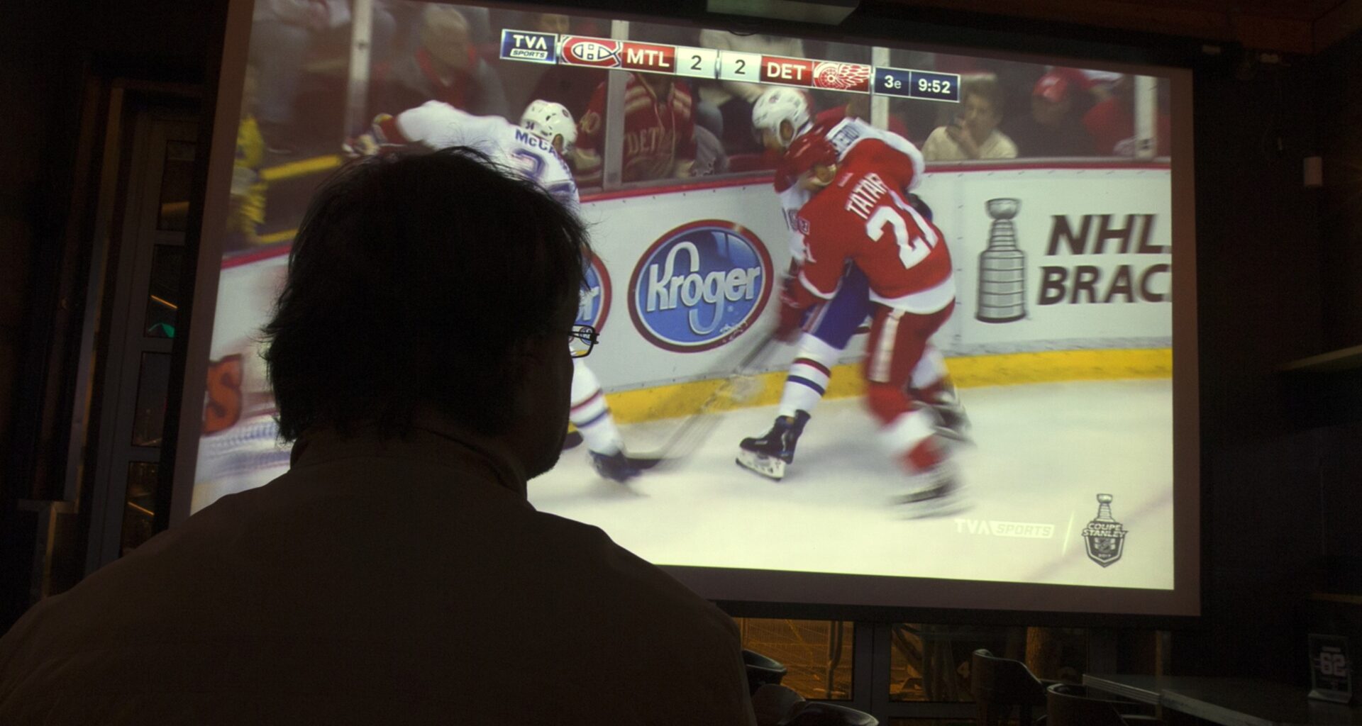 A Montreal Canadiens fans watches a game on TV in a dark room.