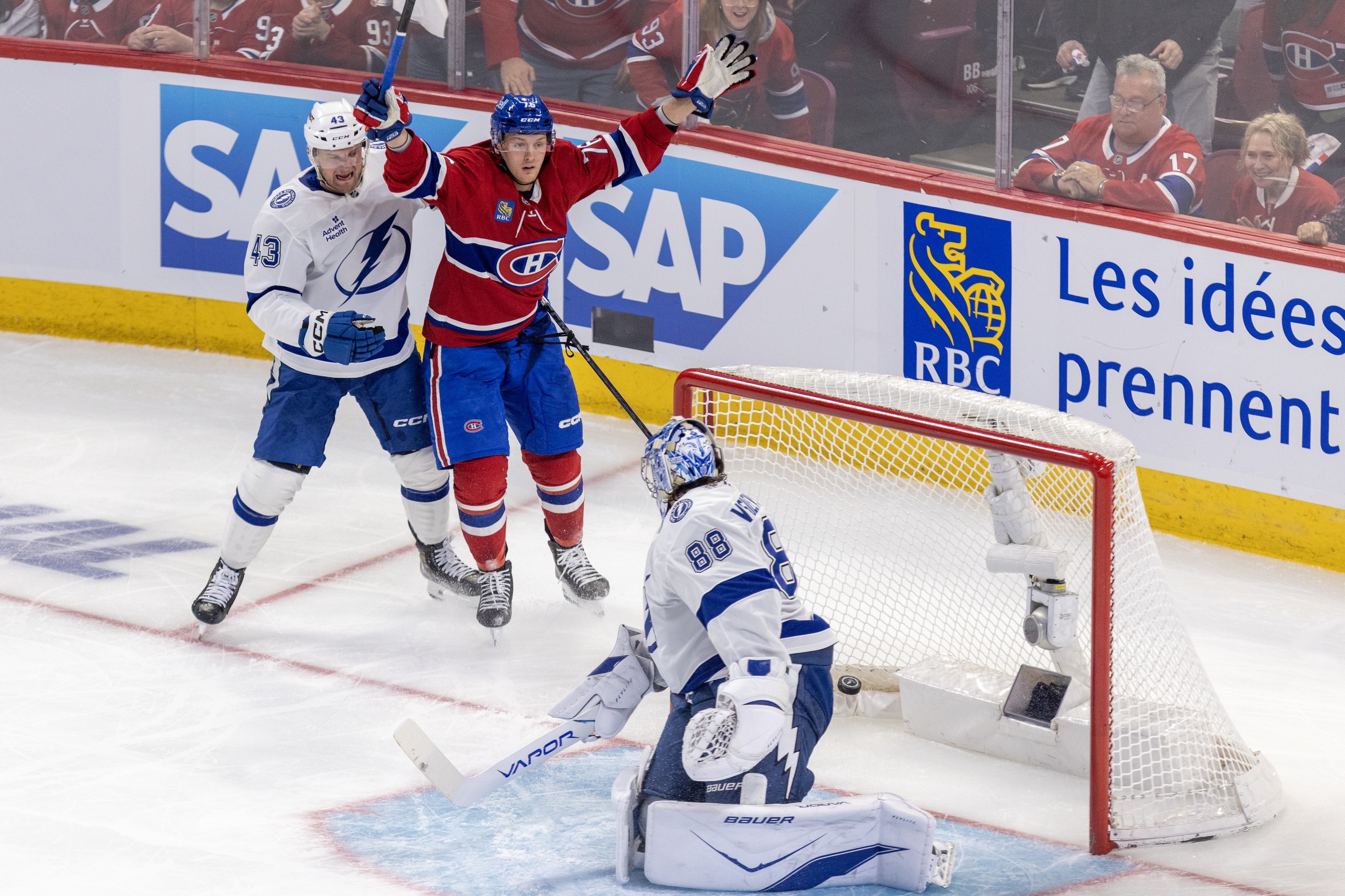 Montreal Canadiens' Zachary Bolduc celebrates after scoring a goal on Tampa Bay Lightning goalie Andrei Vasilevskiy while being checked by Tampa defenceman Darren Raddysh.