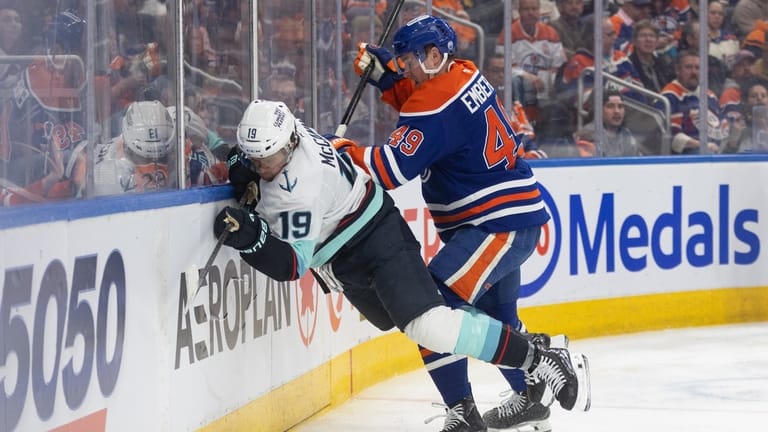 Seattle Kraken's Jared McCann (19) is checked by Edmonton Oilers'...