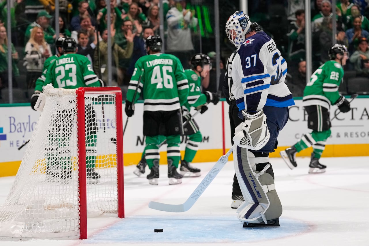 Winnipeg's goalie fishes the puck out of the net while four Dallas Stars celebrate in the background.