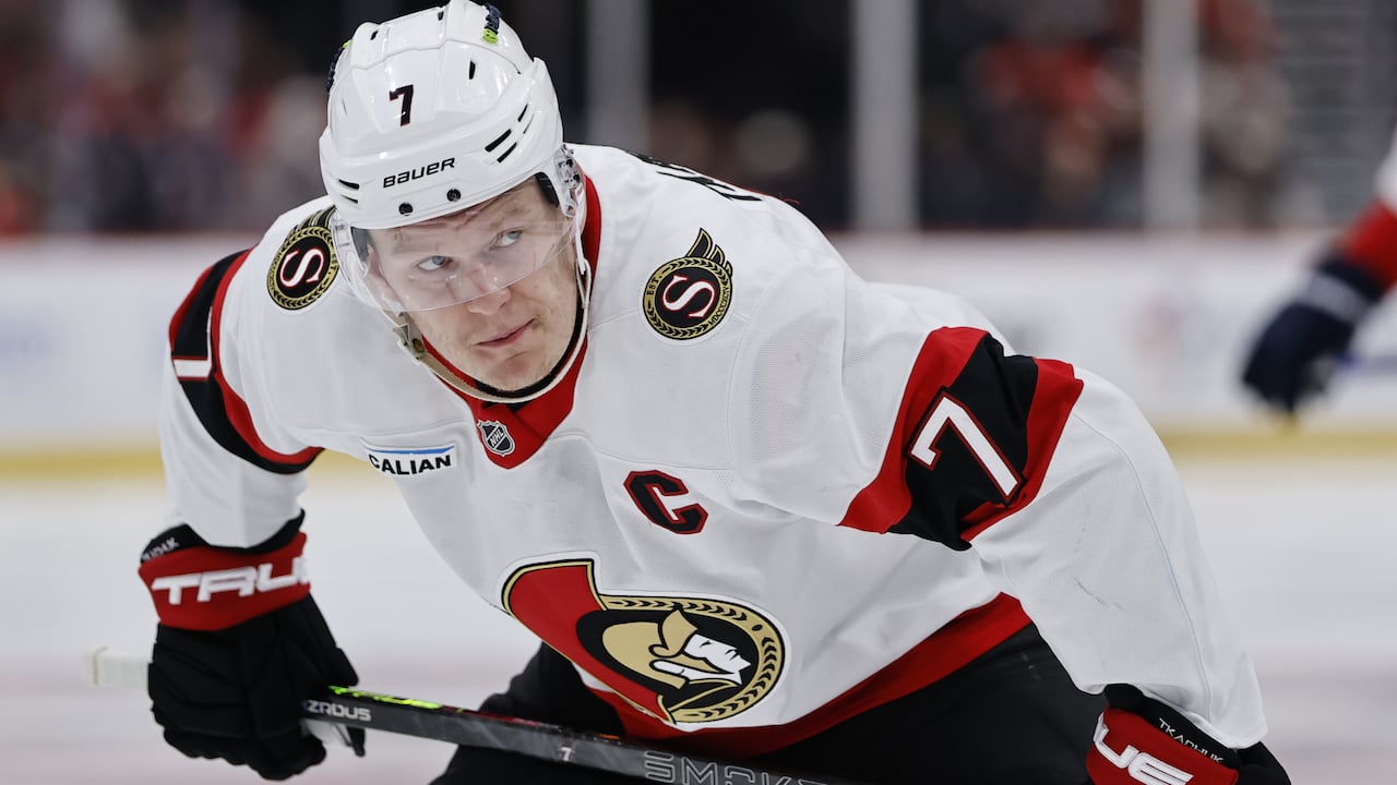 A male ice hockey captain prepares to take a face off.