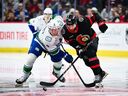 Brock Boeser and Michael Amadio of the Ottawa Senators battle during Jan. 13 game at the Canadian Tire Centre in Kanata, Ont.