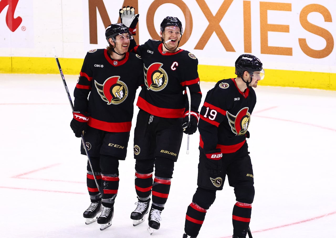Three hockey players celebrate a goal.