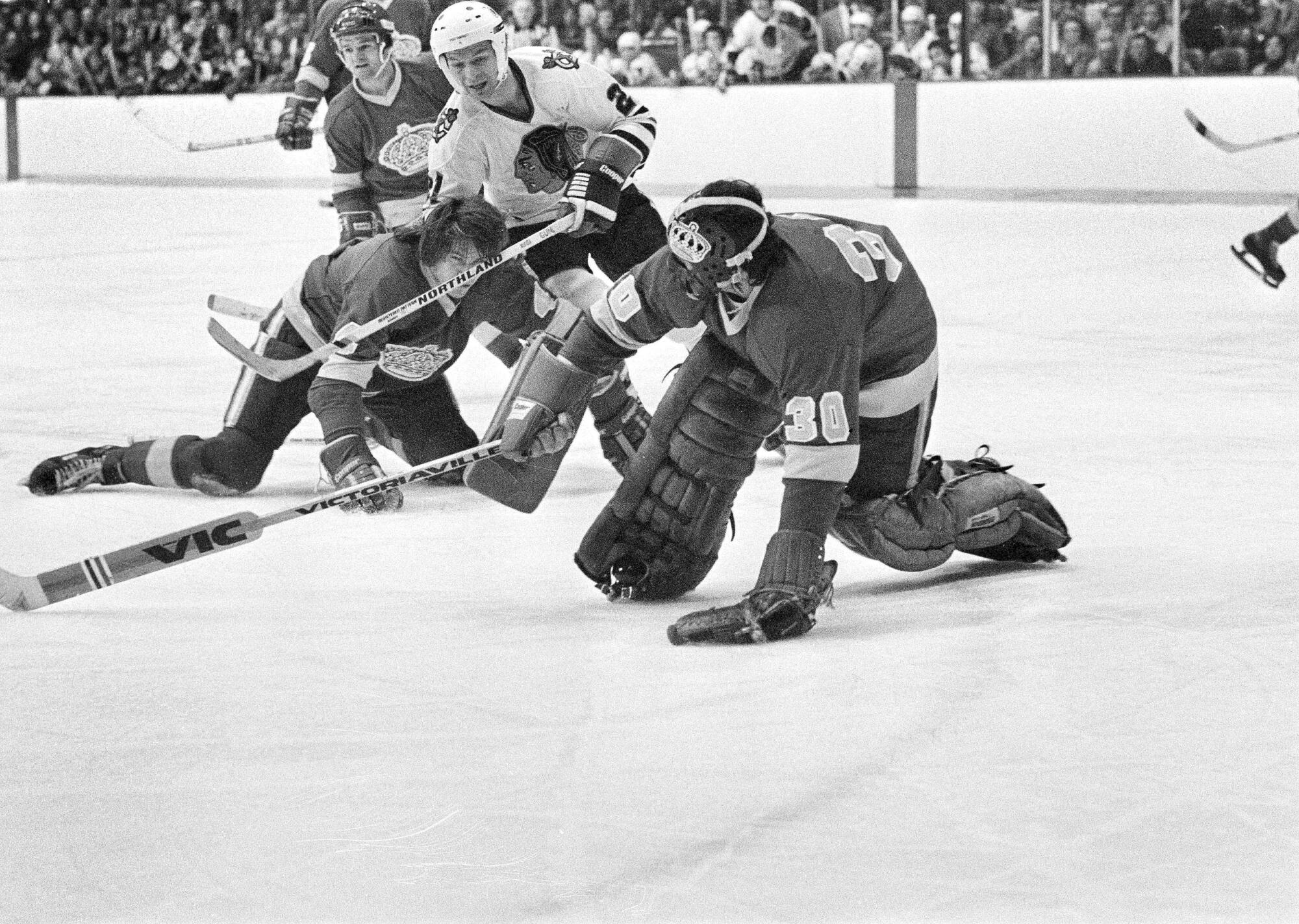Kings goaltender Rogie Vachon tries to avoid a collision with Chicago's Stan Mikita and the Kings' Dave Hutchison.