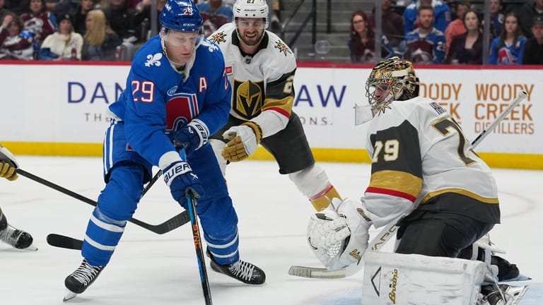 Colorado Avalanche center Nathan MacKinnon, left, puts a shot on...