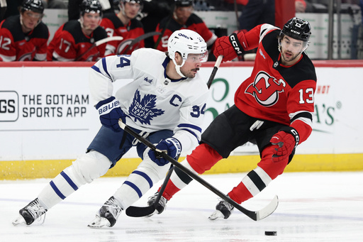 FILE - Toronto Maple Leafs center Auston Matthews (34) controls the puck past New Jersey Devils center Nico Hischier (13) during the second period of an NHL hockey game, March 4, 2026, in Newark, N.J. (AP Photo/Adam Hunger, File)
