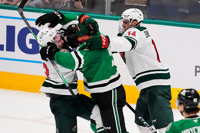 Minnesota Wild's Quinn Hughes, left, Dallas Stars' Mikko Rantanen, center, and Joel Eriksson Ek (14) fight in the third period of an NHL hockey game Thursday, April 9, 2026, in Arlington, Texas. (AP Photo/Tony Gutierrez)
