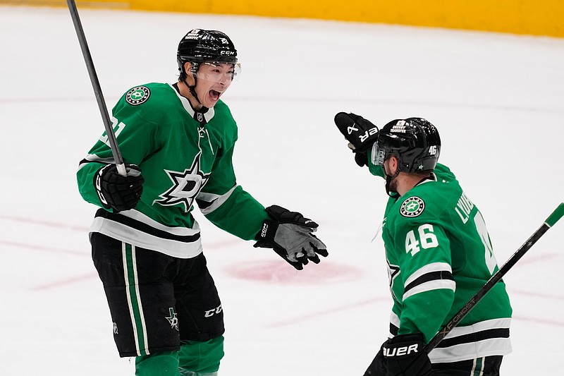 Dallas Stars left wing Jason Robertson (21) and Ilya Lyubushkin (46) celebrate after Robertson scored in the third period of an NHL hockey game against the Minnesota Wild Thursday, April 9, 2026, in Arlington, Texas. (AP Photo/Tony Gutierrez)
