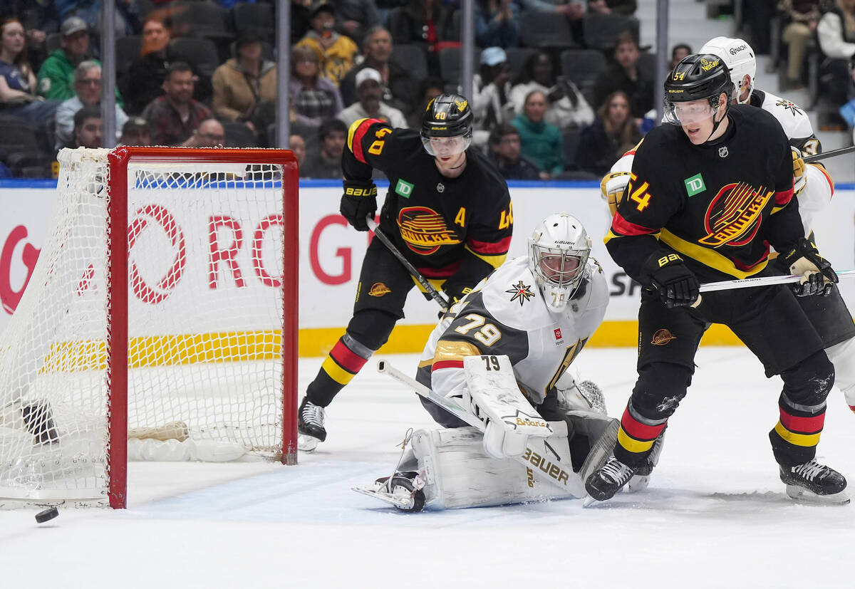 Vegas Golden Knights goalie Carter Hart (79) and Vancouver Canucks' Aatu Raty (54) and Eli ...