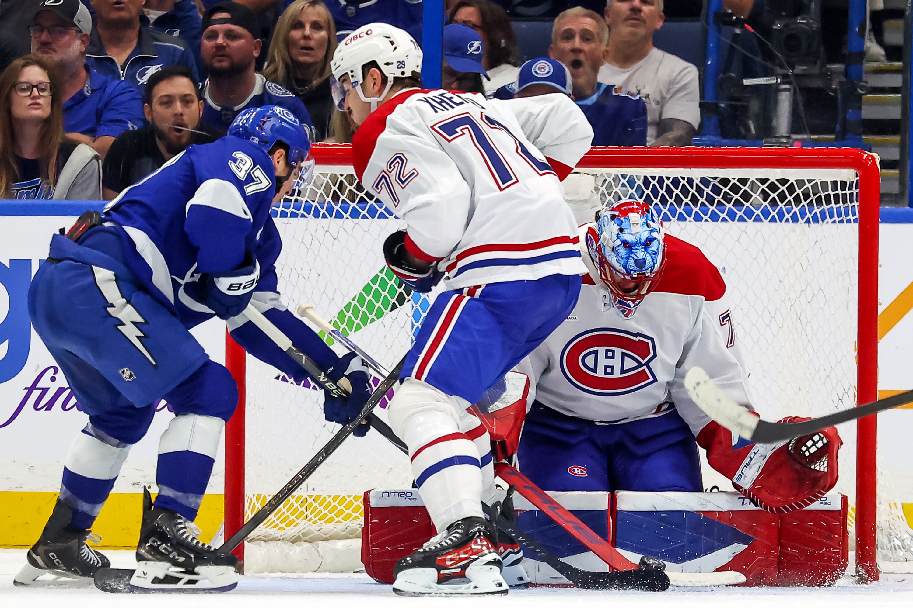 Jakub Dobes #75 of the Montreal Canadiens makes a save against Yanni Gourde #37 of the Tampa Bay Lightning as Arber Xhekaj #72 defends.