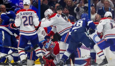 A bunch of Canadiens and Lightning players crowd around a Canadiens goalie bent over on the ice
