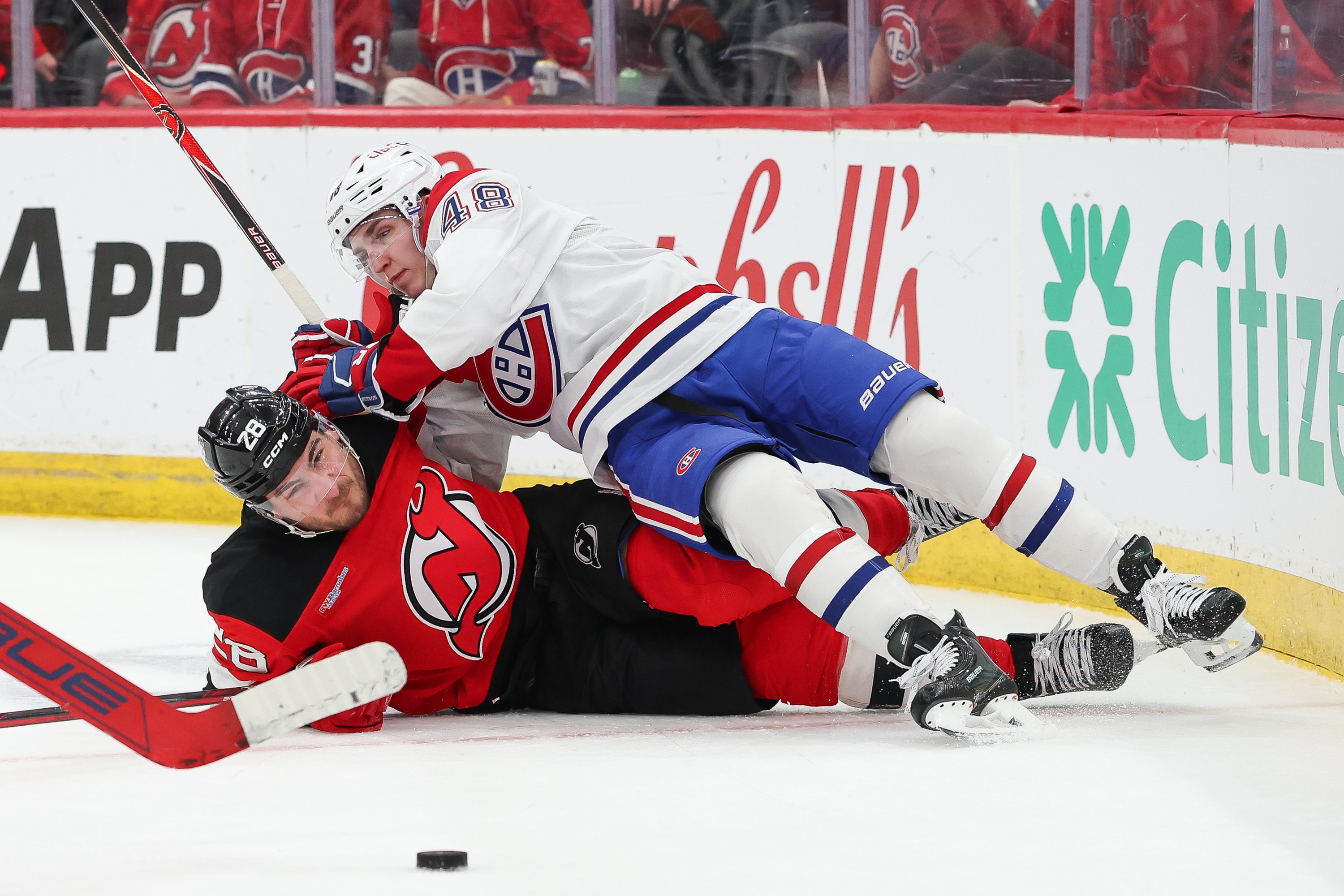 Hockey player lies on top of an opponent during a battle for the puck. 