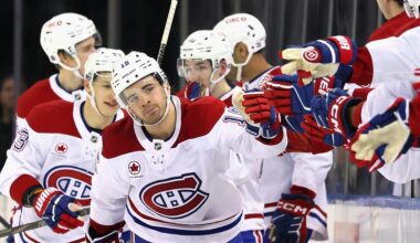 Hockey player skates along the bench to tap gloves with his teammates after scoring a goal.