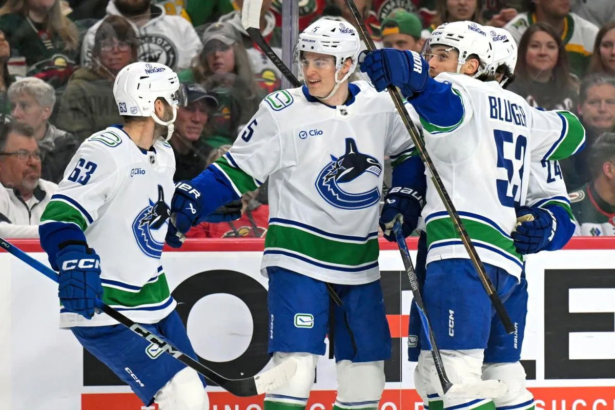 Vancouver Canucks defensemen Tom Willander (5) celebrates his goal against the Minnesota Wild with forward Max Sasson (63) and forward Teddy Blueger (53) during the first period at Grand Casino Arena.