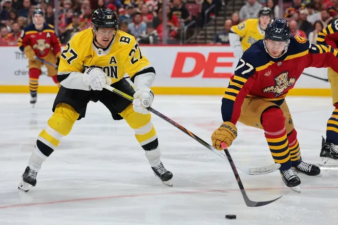 Feb 4, 2026; Sunrise, Florida, USA; Boston Bruins defenseman Hampus Lindholm (27) and Florida Panthers defenseman Niko Mikkola (77) battle for the puck during the second period at Amerant Bank Arena.