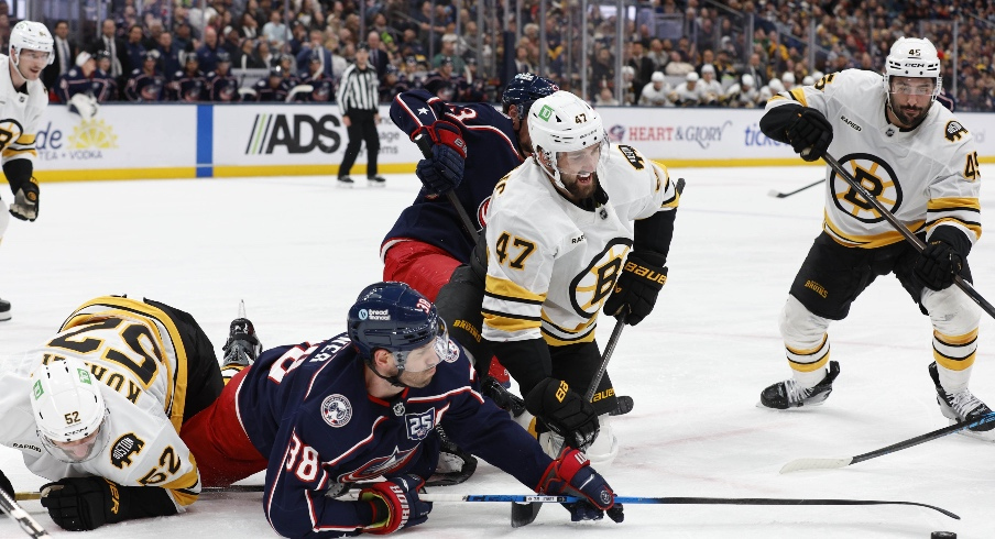Mar 29, 2026; Columbus, Ohio, USA; Columbus Blue Jackets center Boone Jenner (38) reaches for the loose puck with Boston Bruins center Mark Kastelic (47) during the second period at Nationwide Arena.