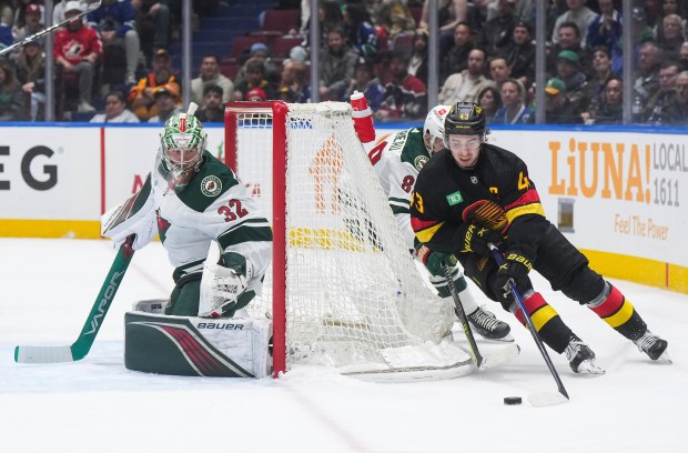 A player with the puck behind the Wild's net