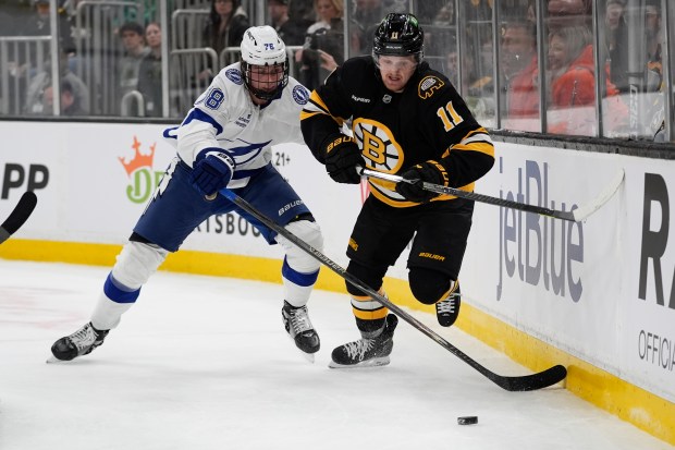 Boston Bruins center Casey Mittelstadt, right, and Tampa Bay Lightning defenseman Emil Lilleberg chase the puck behind the Lightning net during the first period of an NHL game, Saturday, April 11, 2026, in Boston. (AP Photo/Robert F. Bukaty)