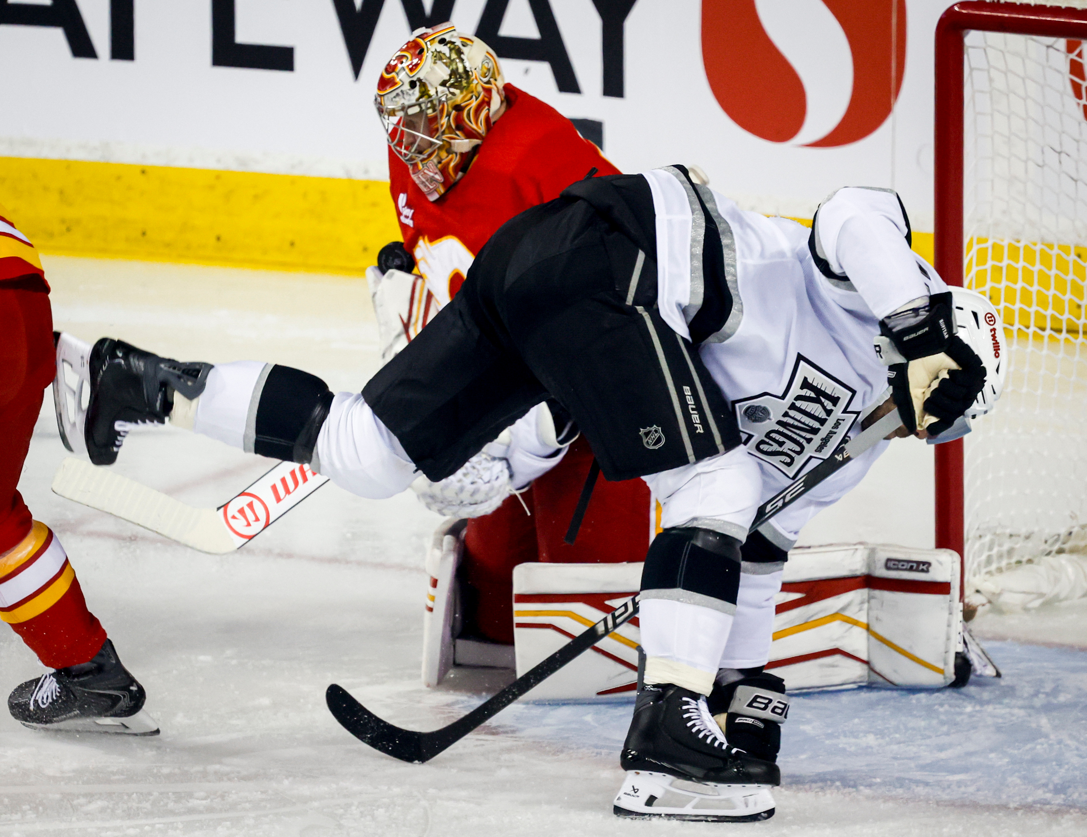 Kings captain Anze Kopitar, right, crashes into Calgary Flames goalie...