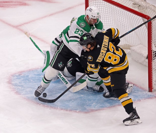 Boston Bruins center Marat Khusnutdinov, right, stuffs the puck under Dallas Stars defenseman Esa Lindell, left, at Dallas Stars goaltender Jake Oettinger as the Bruins take on the Stars at TD Garden. (Staff photo by Stuart Cahill/MNG)
