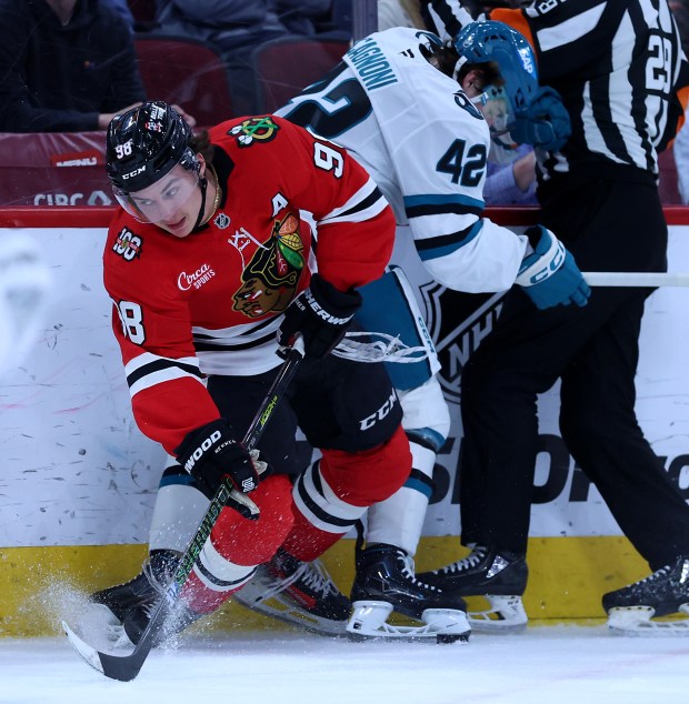 Blackhawks center Connor Bedard battles Sharks defenseman Luca Cagnoni along the boards April 15, 2026, at the United Center. (Chris Sweda/Chicago Tribune)