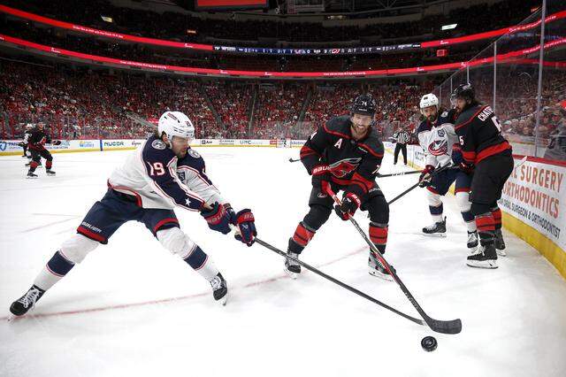Adam Fantilli (19) of the Columbus Blue Jackets and Jaccob Slavin of the Carolina Hurricanes work to obtain possession of the puck during the first period at Lenovo Center on April 2, 2026 in Raleigh, North Carolina.