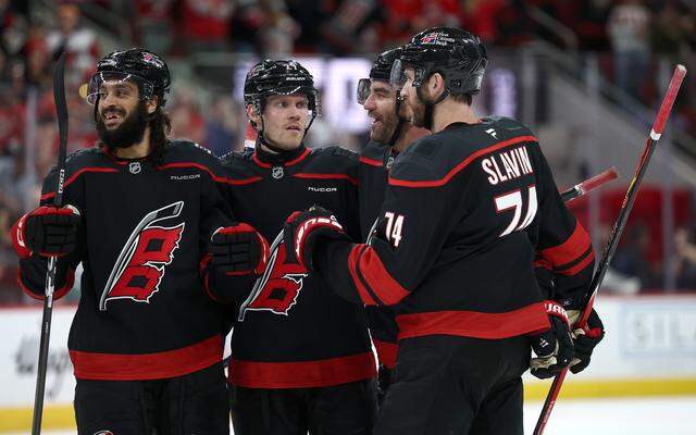 Jordan Martinook, second from right, of the Carolina Hurricanes celebrates with teammates Jalen Chatfield, left, Nikolaj Ehlers, second from left, and Jaccob Slavin, right, following a goal during the second period against the Columbus Blue Jackets at Lenovo Center on April 2, 2026 in Raleigh, North Carolina.