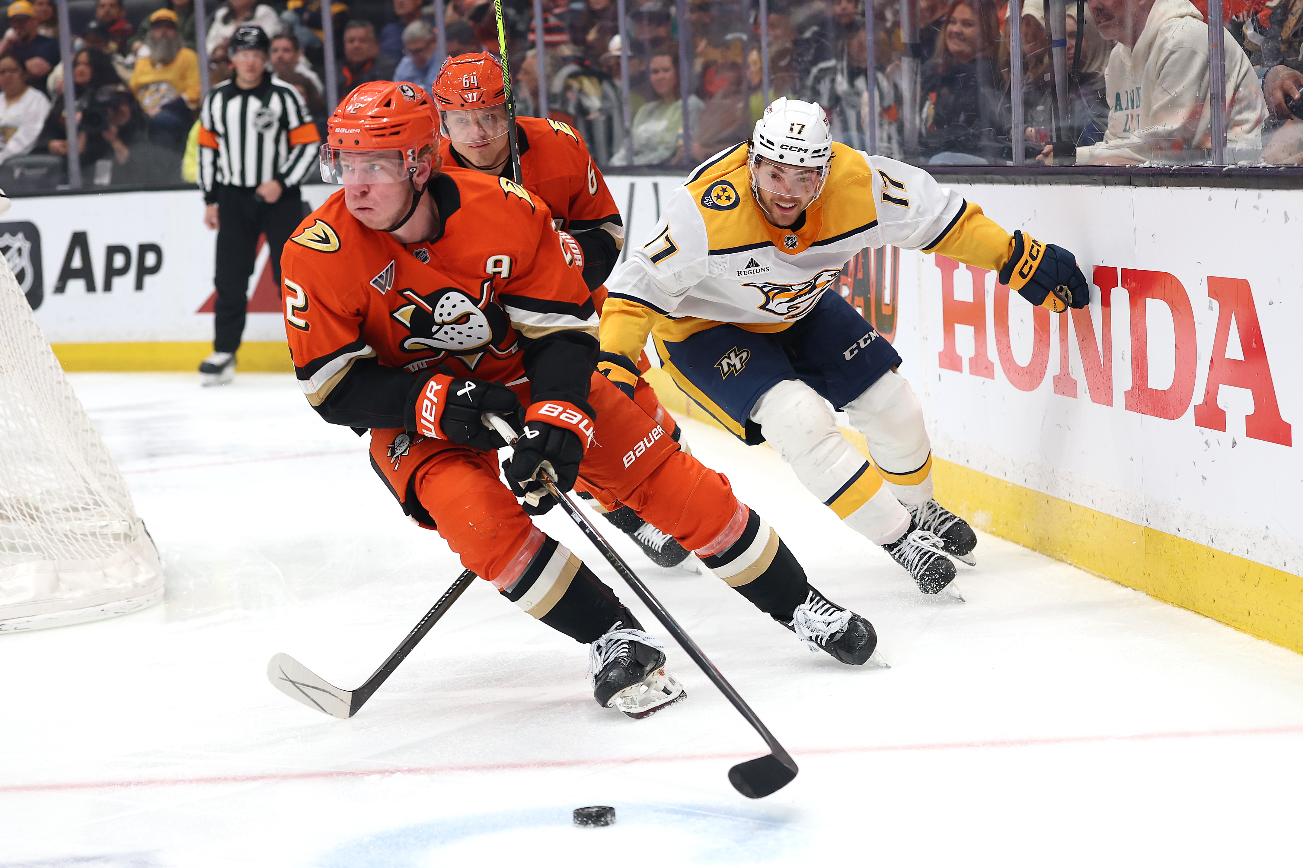 The Ducks’ Jackson LaCombe, left, controls the puck as the...