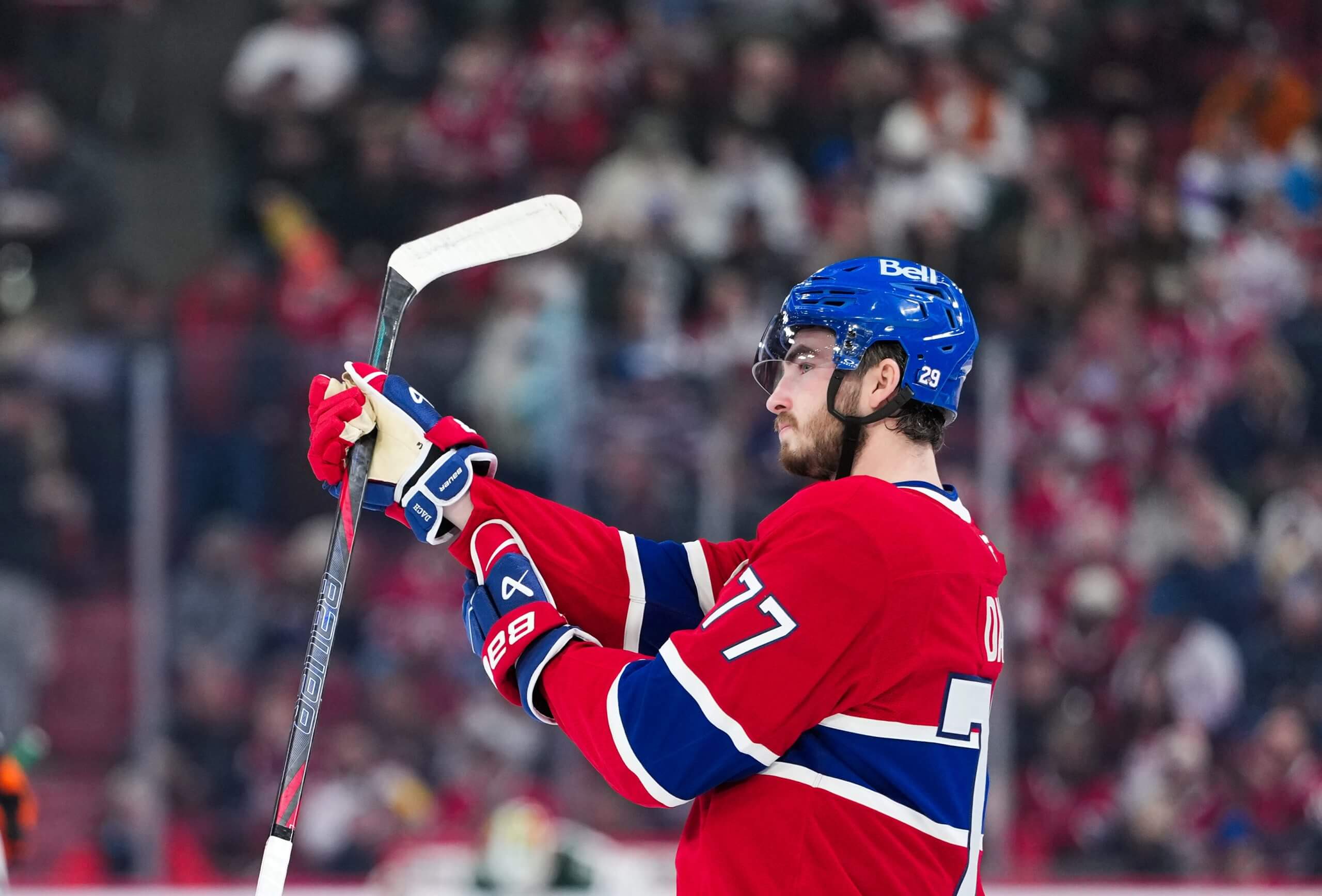 Montreal Canadiens forward Kirby Dach stands on the ice holding his stick in one hand.