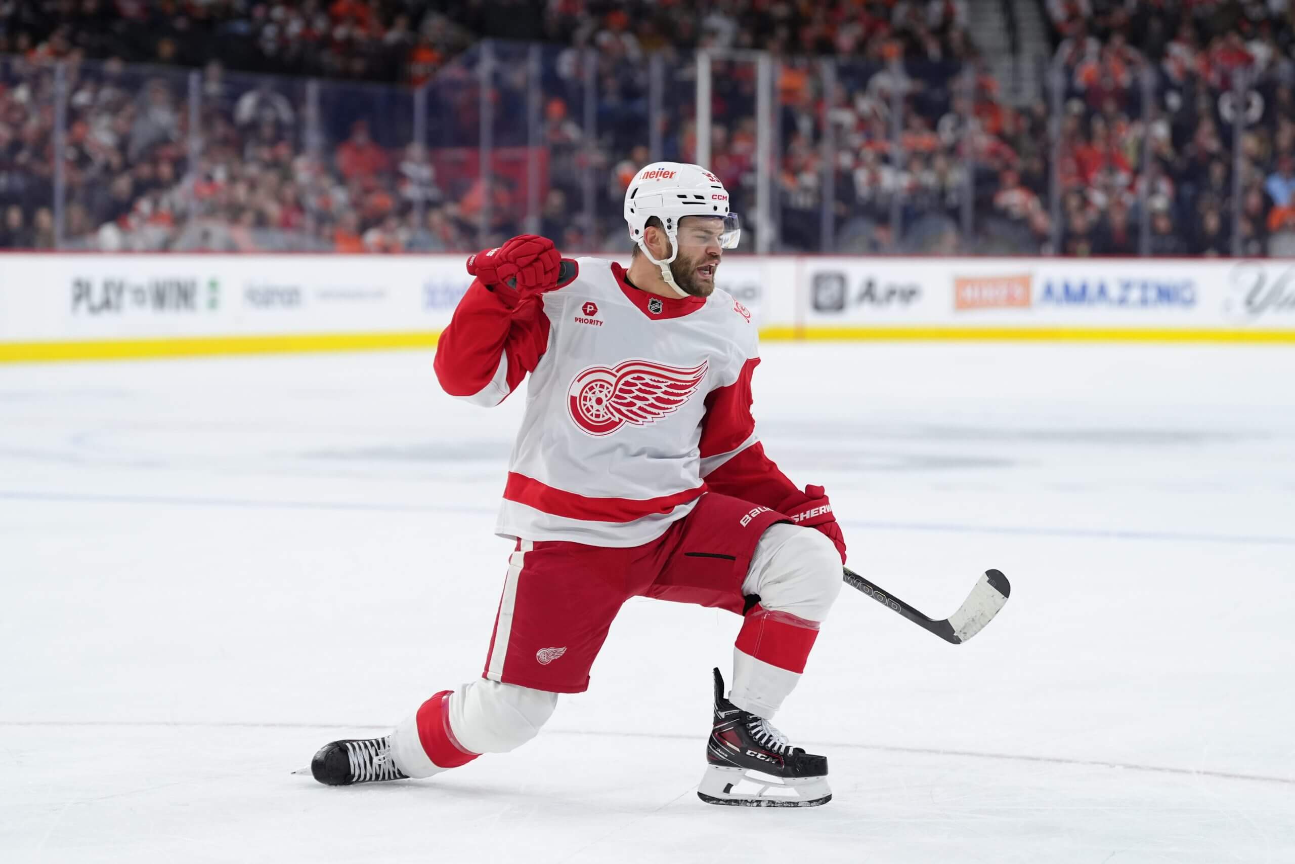 Alex DeBrincat slightly sinks to one knee celebrating after a goal.
