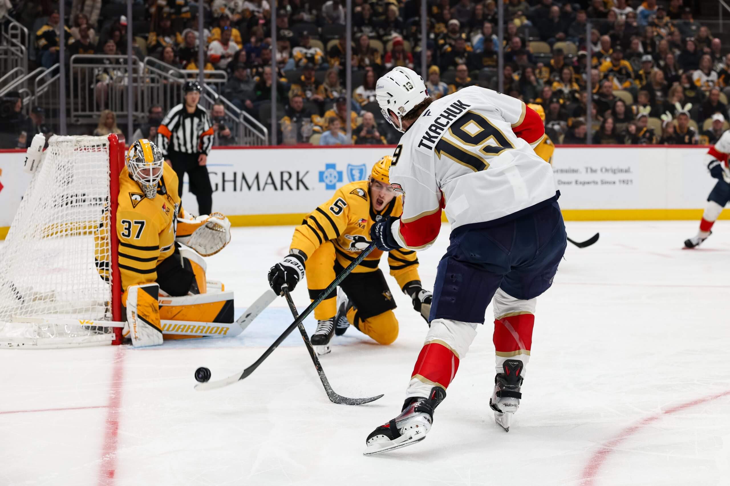 Matthew Tkachuk takes a shot against Penguins goalie Arturs Silovs with a Penguins defenseman trying to block.